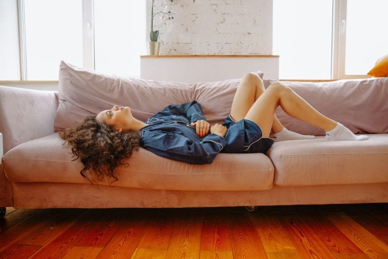 woman lying on the couch clutching her stomach