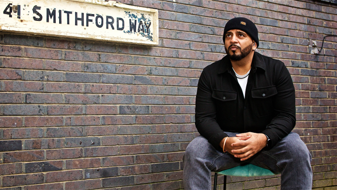 made in India Britain. Rinkoo Barpaga sits on a chair outside a sign that says 41 Smithford Way