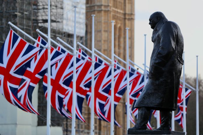 Daytime image of a Churchill statue surrounded by Union Jack flags