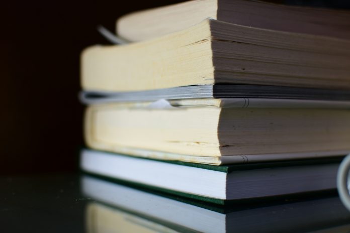 A photo of a stack of books with the spines and covers out of sight.