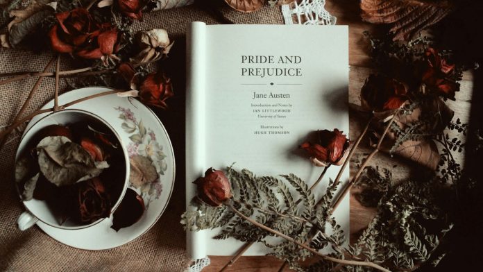 A copy of the book Pride and Prejudice, with the cover folded back, arranged on a table with dried flowers