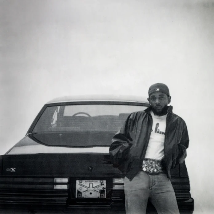 Kendrick Lamar GNX album art, depicting Kendrick Lamar sporting a cap, leather jacket, jeans and a white top while leaning on a black car. The image is in black and white.