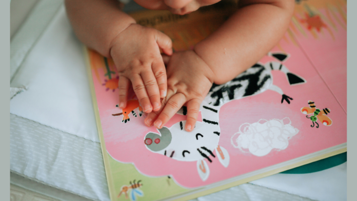 A toddler's hands on a colourful page of a book